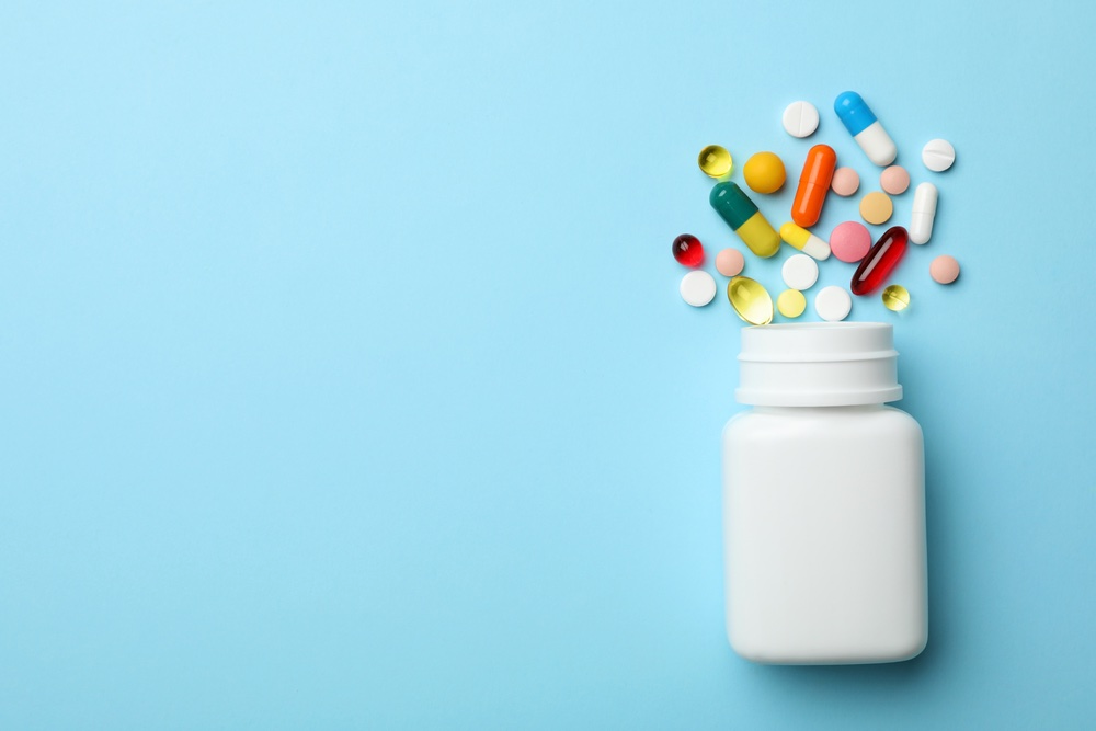 Bottle and Pills Spread Out on Blue Background